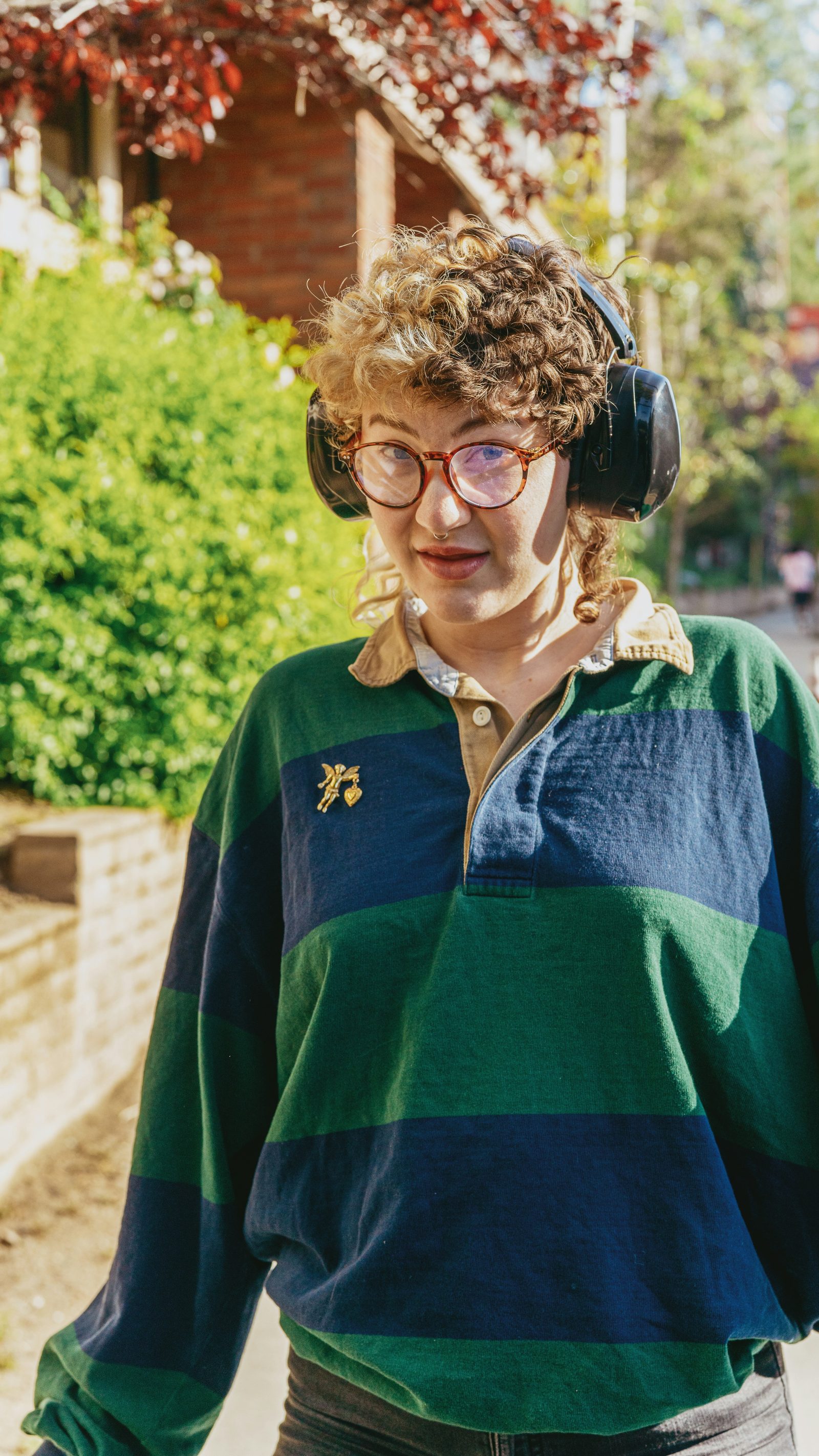 A young adult wearing ear defenders outside their home
